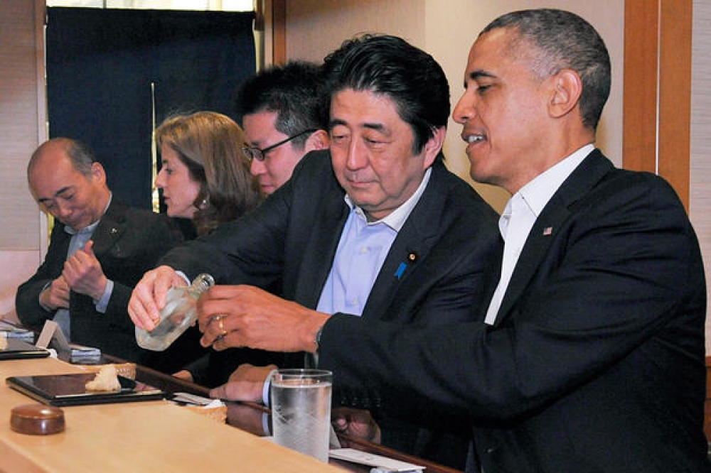 US President Obama enjoying some saki with Japan's Prime Minister Shinzo Abe during dinner at a sushi restaurant