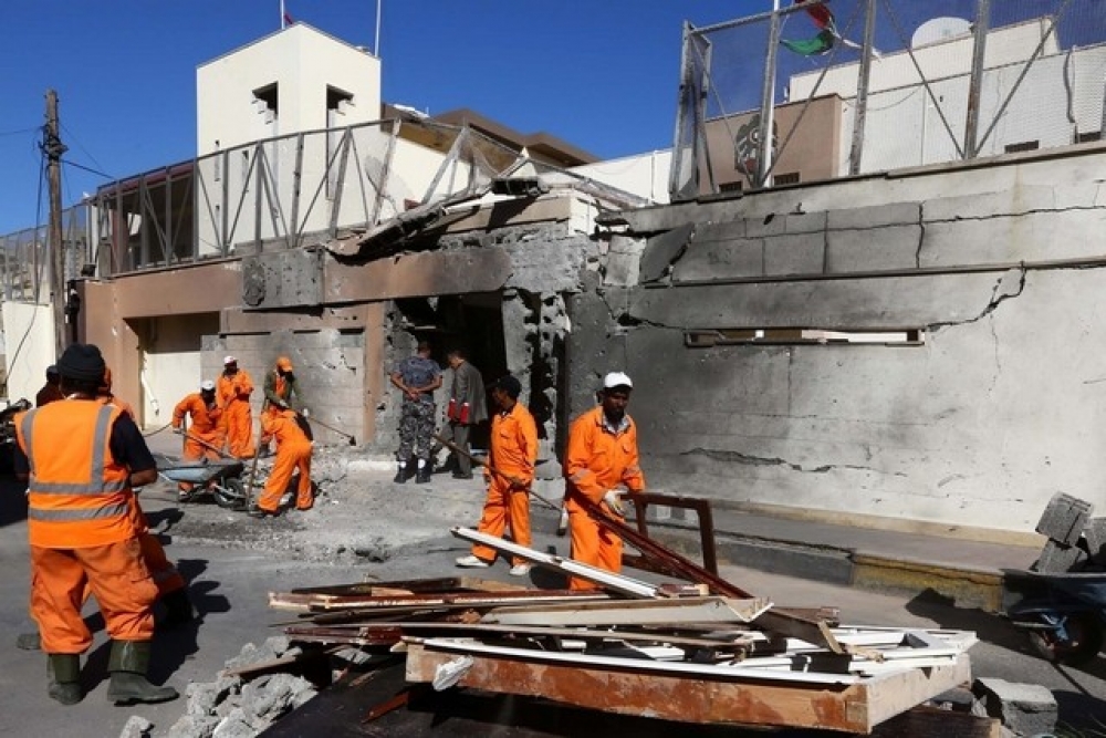 Workers clear the damage outside the UAE embassy building that was targeted by a car bomb in Tripoli, Libya