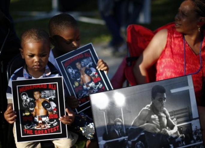 Brandon Liggons, 2, (L) holds an image of Muhammad Ali during the funeral procession for the three-time heavyweight boxing champion in Louisville, Kentucky, U.S., June 10, 2016.