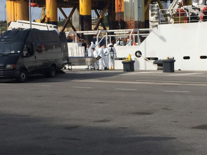 The migrant bodies being placed inside the morgue vans at Boiler Wharf