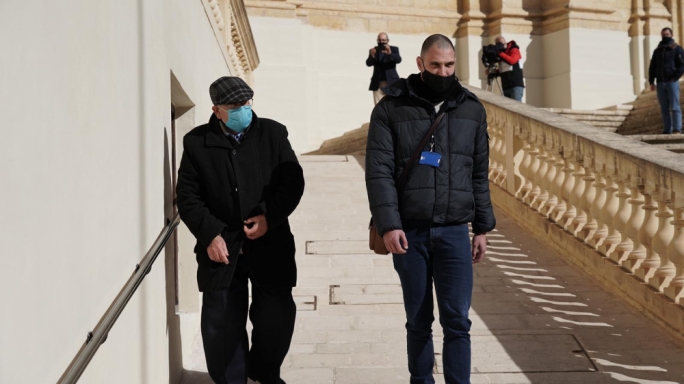 Fr Joseph Sultana (left) being accompanied by police to the waiting prison van after the court sitting was over (Photo: James Bianchi/MaltaToday)