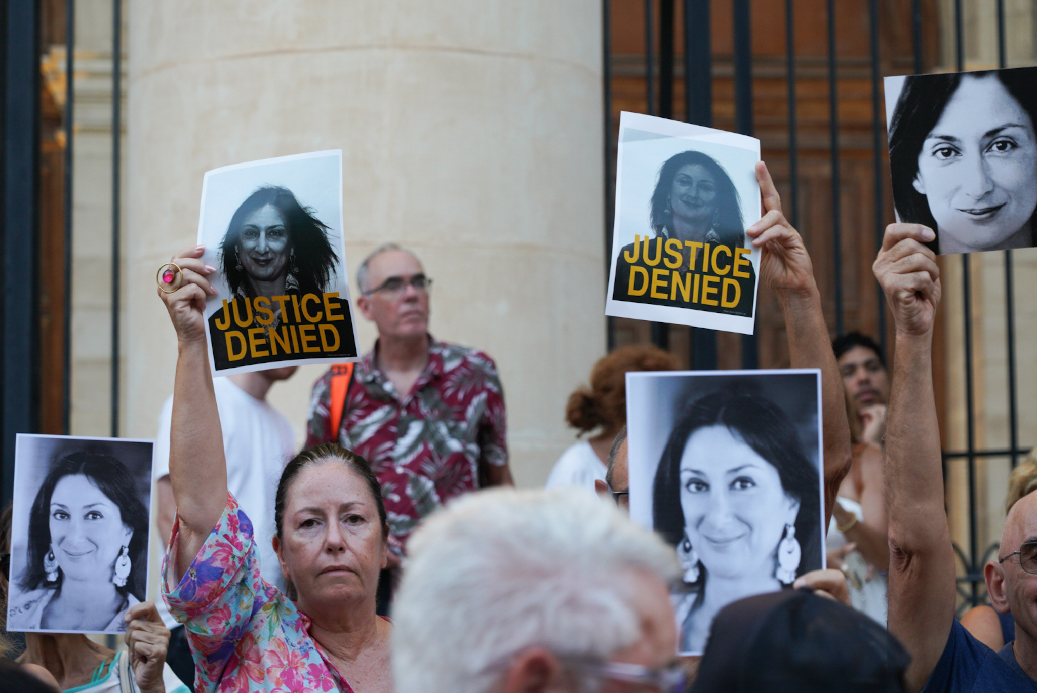 Supporters hold large printed photographs of Daphne Caruana Galizia holding signs which read 