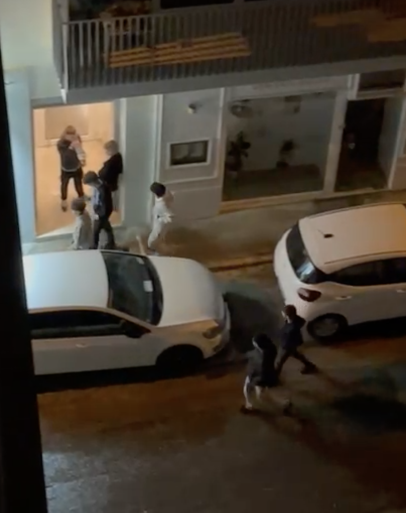 Teens stand at the entrance of an apartment block making excessive noise during late hours