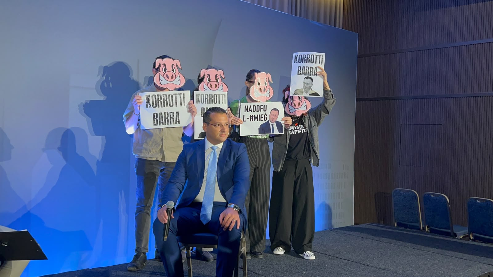 Activists stood behind Planning Minister Jonathan Attard wearing pig masks and holding up signs which read 'Out with the corrupt' and 'Clean up the dirt' (Photo: MaltaToday/Matthew Farrugia)