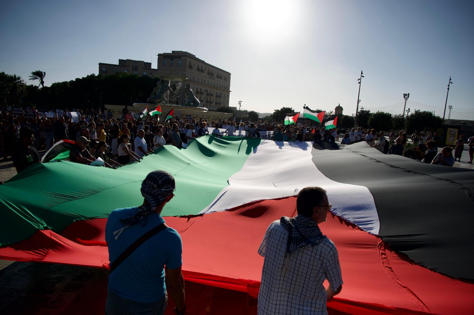  Protestors in Malta holding a large Palestinian flag in Triton Square during a demonstration held in 2025 (Photo: Miguela Xuereb/Newsbook)