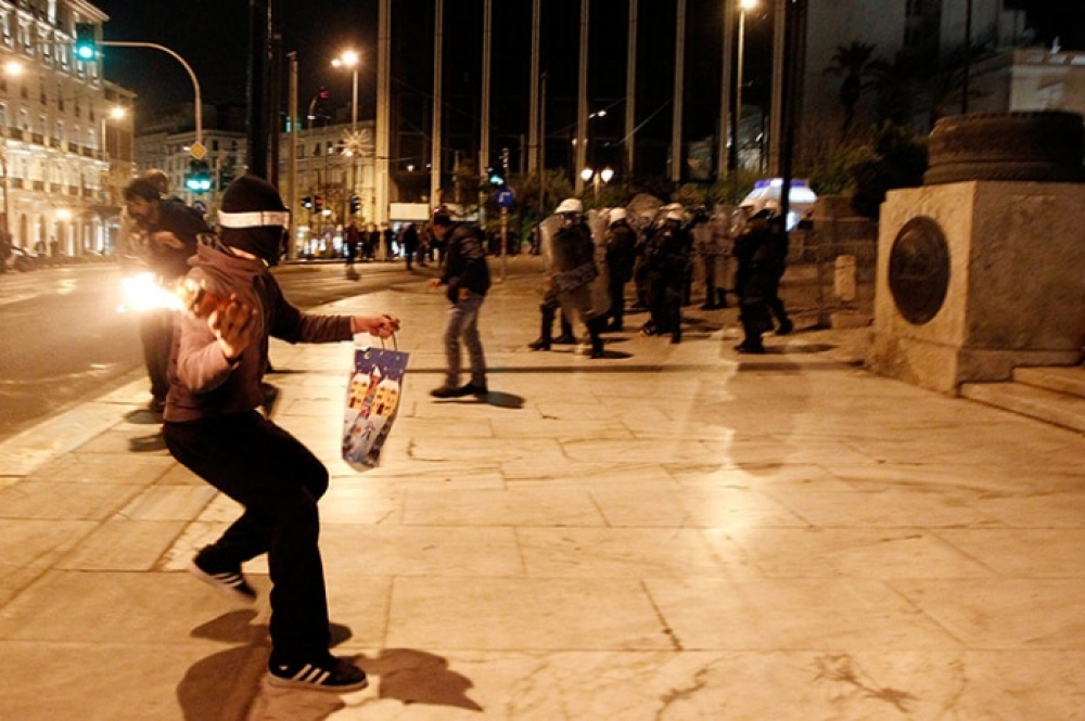 A protestor throws a Molotov cocktail at riot police