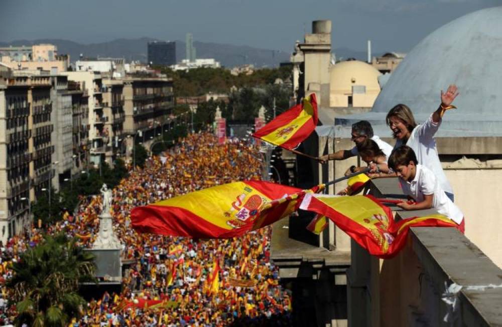 'Catalonia is Spain'. People on a rooftop wave Spanish flags during a march in downtown Barcelona, Spain (Photo: NY Daily News)