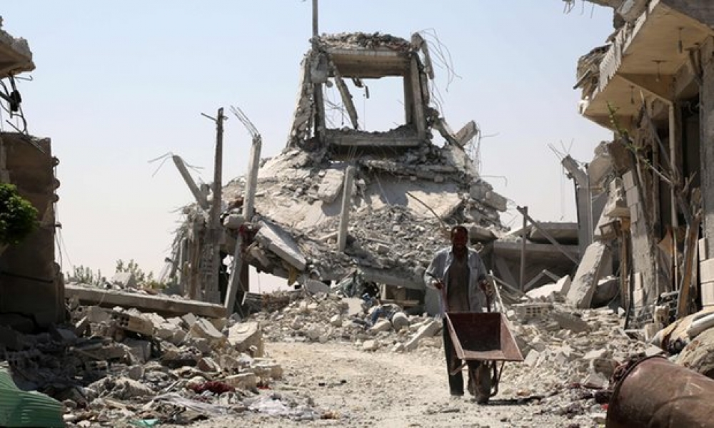 A Syrian man pushes a wheelbarrow past collapsed buildings in the northern Syrian town of Manbij, near the village that was hit (Photo: AFP)