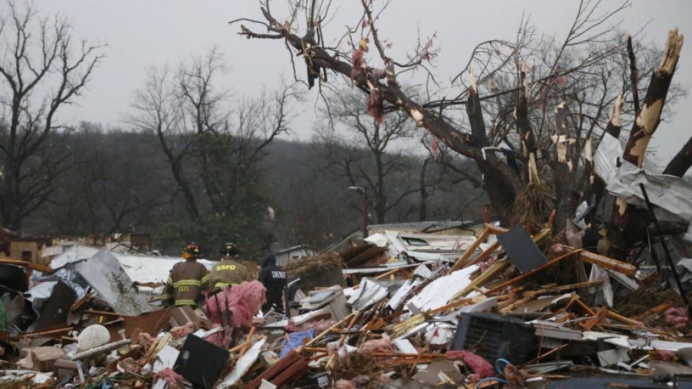 Rescue workers stand amid the debris of a destroyed home
